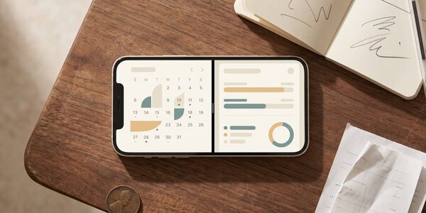 Editorial flat-lay of a smartphone displaying a cash-advance app interface next to a payday-calendar visualization on a worn desk